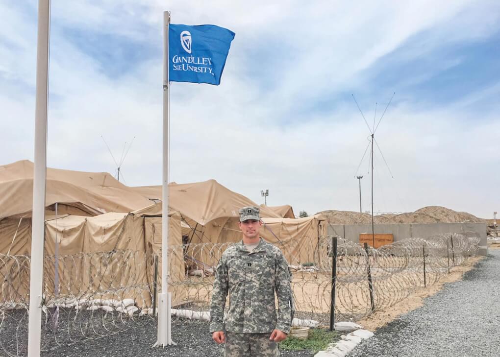 Masters in his army fatigues on base with a GVSU flag flying